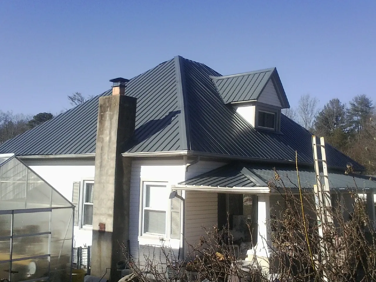 Dark blue standing seam metal roof on a white farmhouse with dormer — Slate & Tile Roof Repair by Roofing Brothers in Rush City