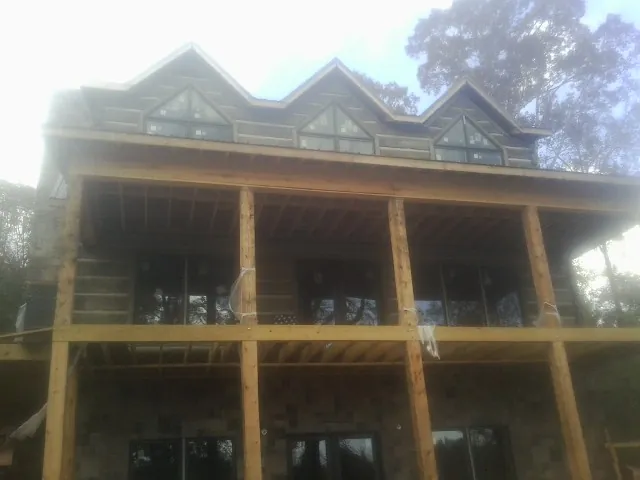 Dormers and porch framing on a large log home under construction — Roof Coating work by our crew in Rush City