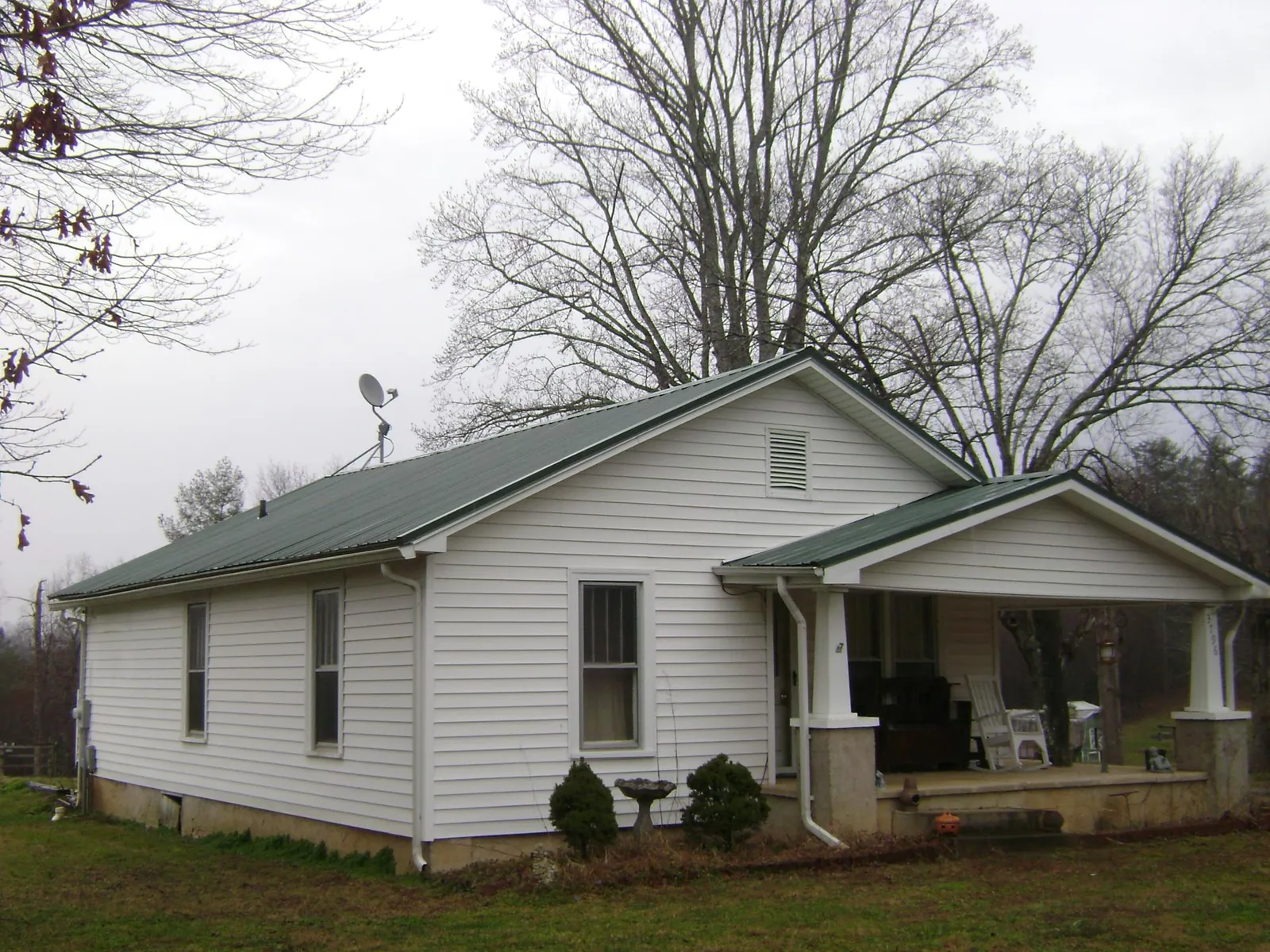 Green metal roof on a white bungalow with a side porch in Rush City