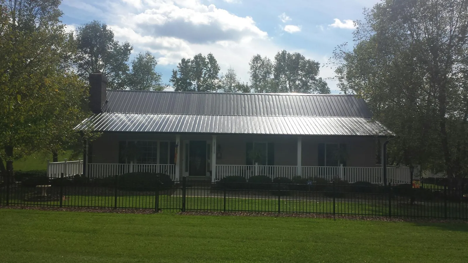 Gray metal roof on a brick ranch with a full width front porch — Gutter Guard Installation work by our crew in Rush City