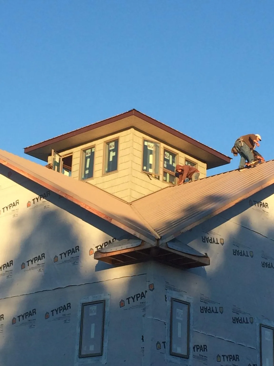 Roofers working around a rooftop cupola on a new metal roof at sunset — Roof Waterproofing in Rush City by Roofing Brothers